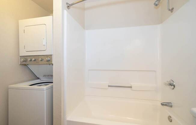 A white bathroom with a tub, toilet, and washing machine.