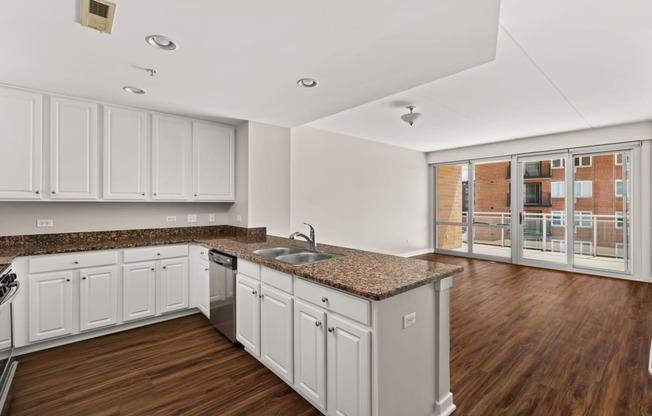 a kitchen with white cabinets and granite counter tops and a window