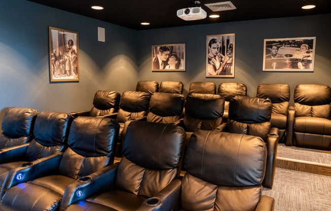 a home theater room with leather chairs and pictures on the wall