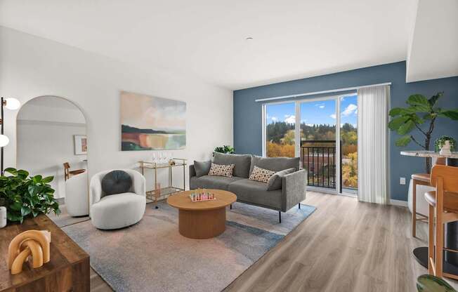 A living room with a large window and a painting on the wall.