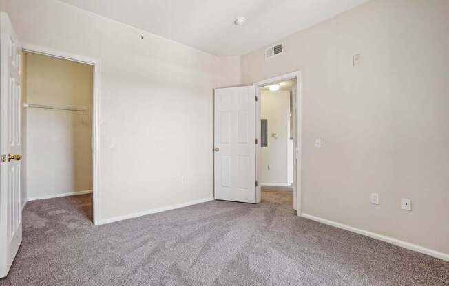 A room with a carpeted floor and two doors.