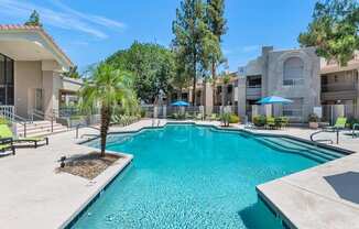 A swimming pool surrounded by a concrete patio and a few trees.