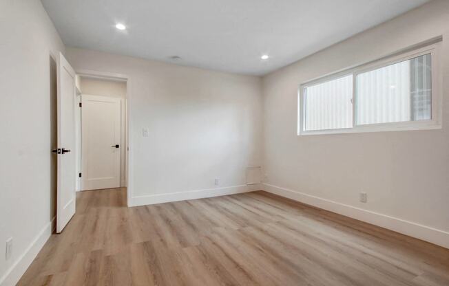 an empty living room with white walls and wood floors