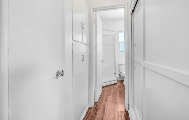 a hallway with white walls and a door to a bathroom