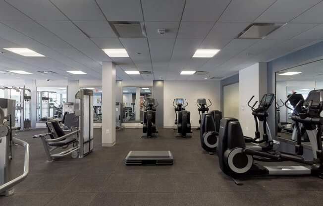 a large fitness room with cardio machines and weights