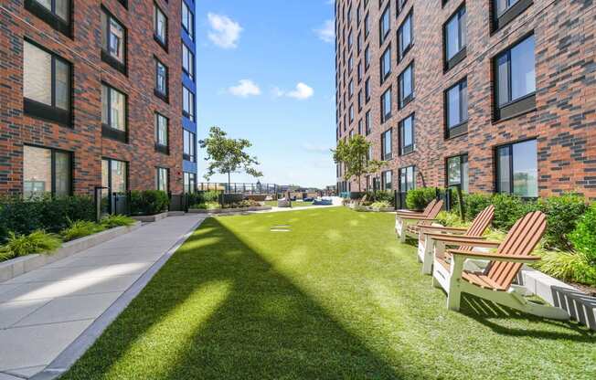 a courtyard with chairs and grass in front of a brick building