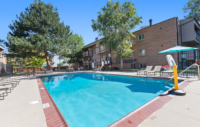 A swimming pool surrounded by trees and chairs.