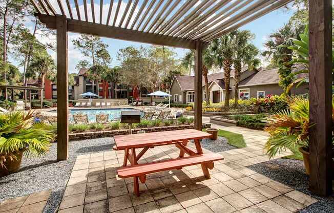 A wooden picnic table is in the middle of a patio.