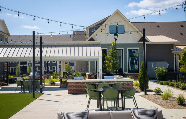 a patio with tables and chairs in front of a house