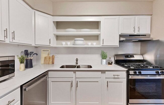 a white kitchen with stainless steel appliances and white cabinets