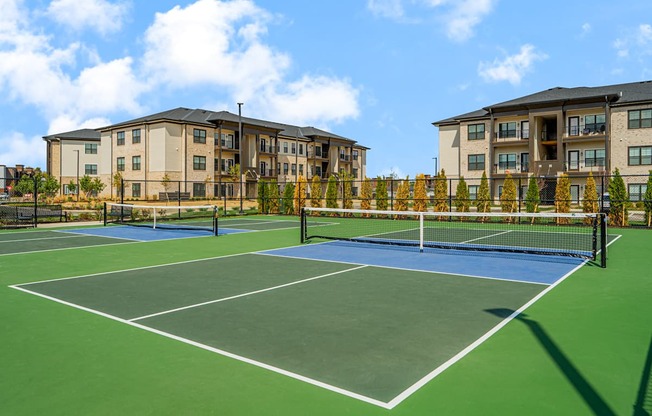 A tennis court is surrounded by apartment buildings.