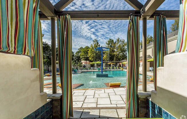 A pool area with striped curtains and a view of the sky.