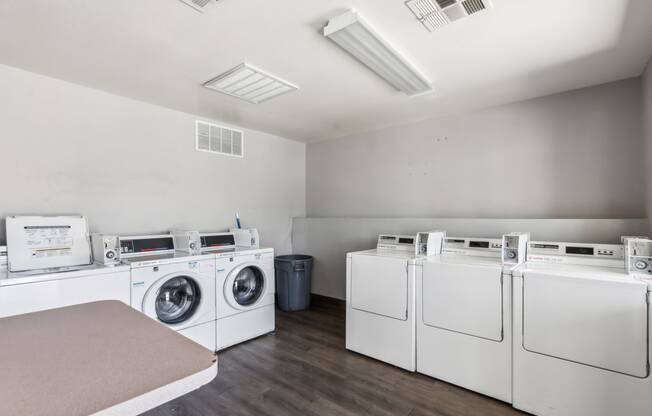 a laundry room with washers and dryers and a row of washing machines