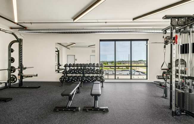 a gym with weights machines and a view of a window at The Standard on 32nd, North Dakota