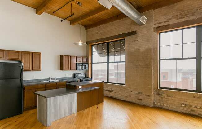 A kitchen with wooden floors and a black refrigerator.