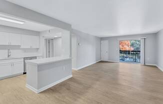 the living room and kitchen of a new home with white cabinets and a large window