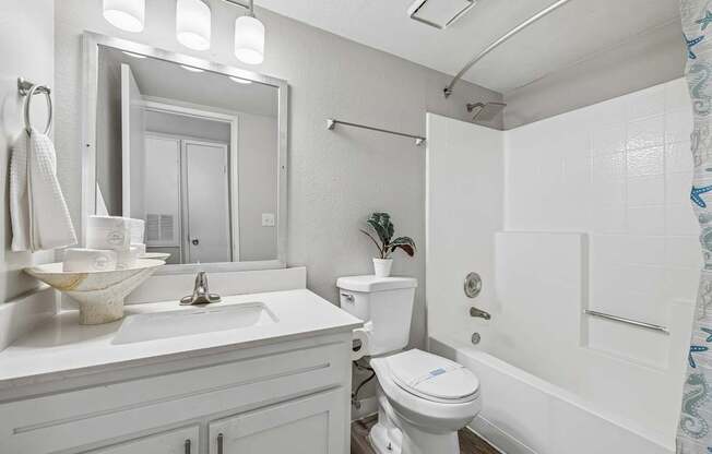 A white bathroom with a toilet, sink, and mirror.