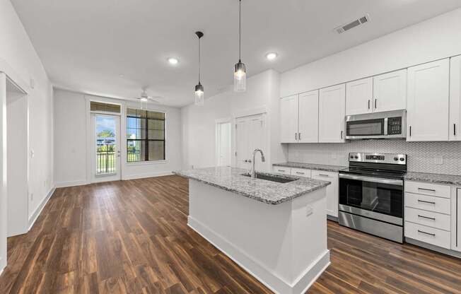 A modern kitchen with white cabinets and a granite countertop.