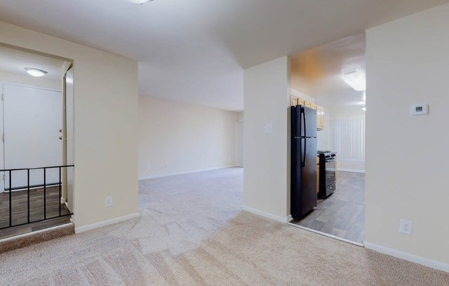 a renovated living room and kitchen with a black refrigerator