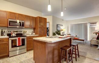 a kitchen with an island and stools in front of a living room with a couch and