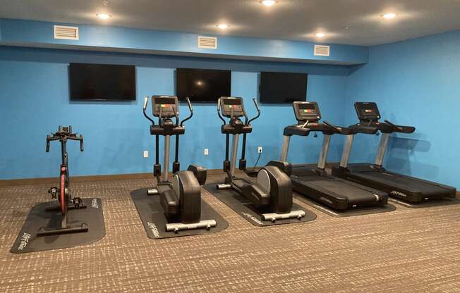 a row of exercise bikes in a gym with televisions