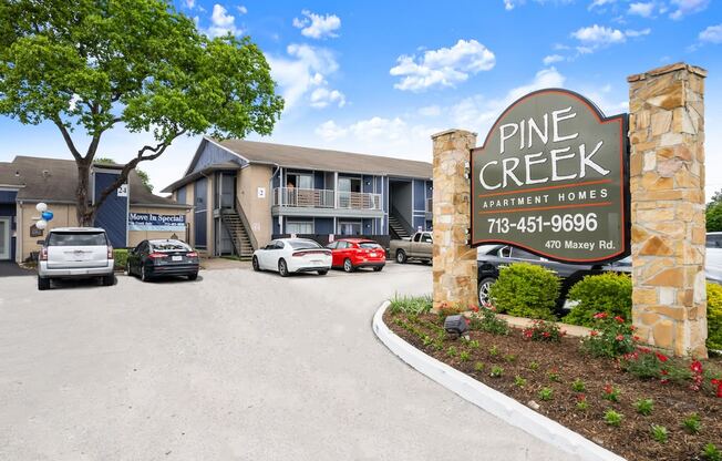 a sign for pine creek retirement homes with cars parked in front