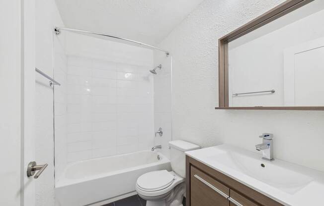 A white toilet sits next to a white sink in a small bathroom.