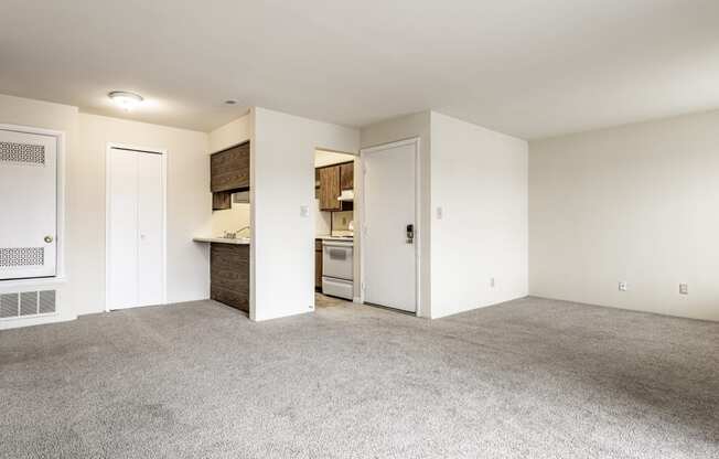 an empty living room and kitchen with white walls and carpet