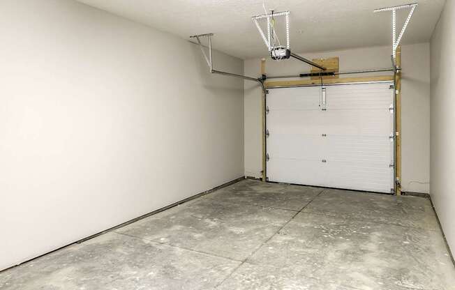 A garage with a white door and a concrete floor.