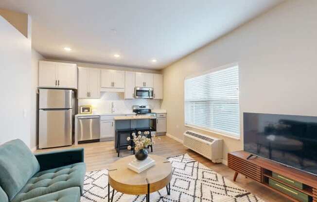 A modern kitchen with a green sofa and a coffee table in the foreground.