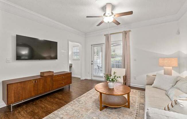 A living room with a wooden coffee table and a flat screen TV mounted on the wall.