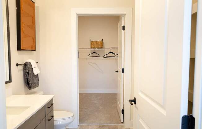 A bathroom with a toilet, sink, and a closet with a hanger.