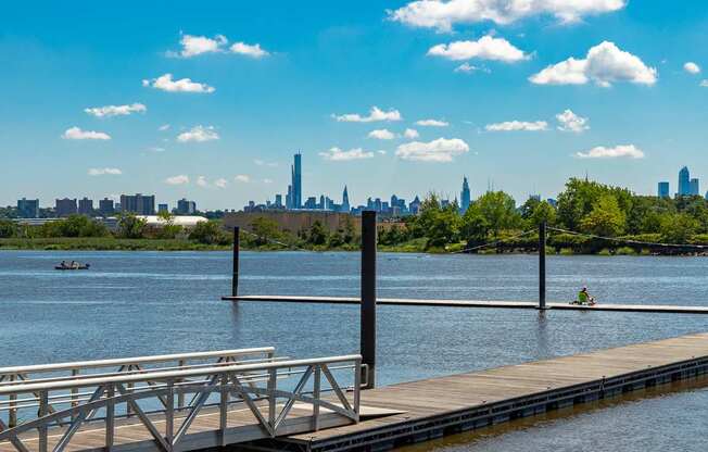A dock extends into a calm body of water with a city skyline in the distance at Vermella Lyndhurst apartments, New Jersey, 07071