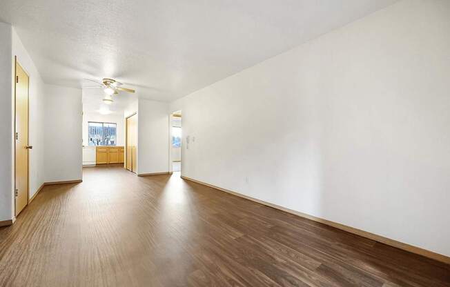 A long empty room with wooden floors and white walls.