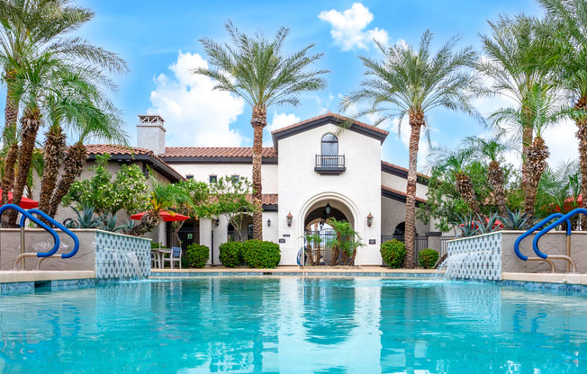 a swimming pool in front of a house with palm trees