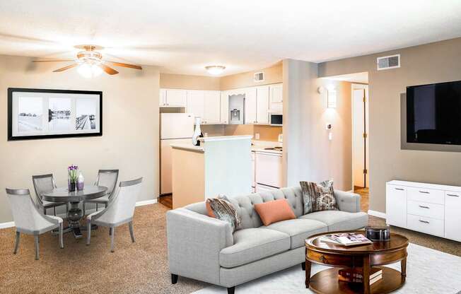 A living room with a grey couch, a coffee table, and a dining table with chairs.