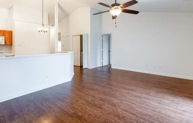 an empty living room with wood flooring and a ceiling fan