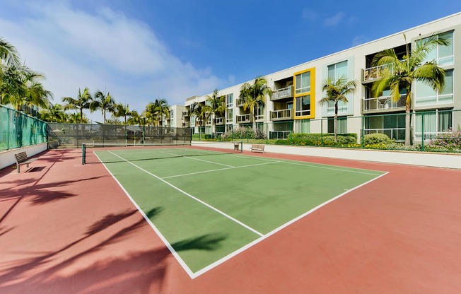 A tennis court is surrounded by a green fence and palm trees at Marina Harbor, California, 90292