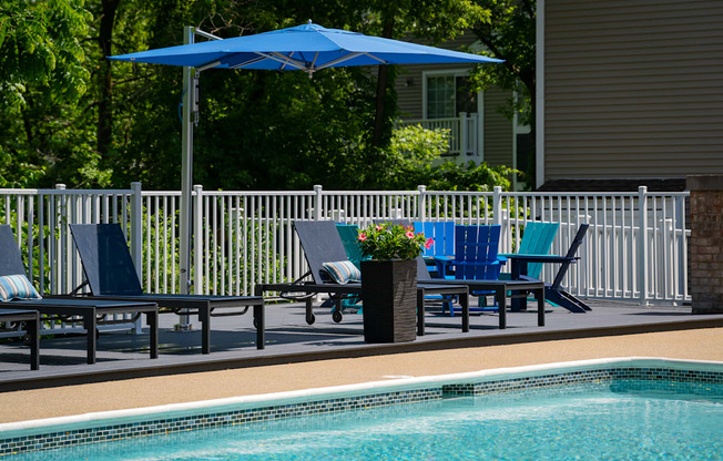 a swimming pool with blue chairs and a blue umbrella