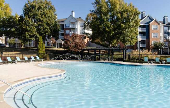 A large swimming pool surrounded by trees and chairs.