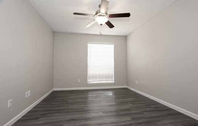 an empty living room with a ceiling fan and a window