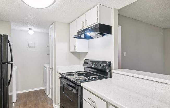 A kitchen with a black stove top oven and white cabinets.