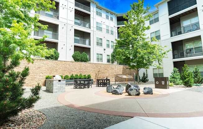 A courtyard with a bench and a tree in front of apartment buildings.