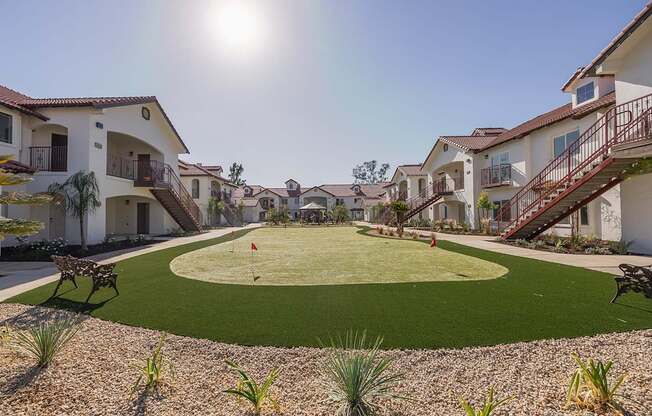 A sunny day at the putting green in the courtyard of apartment buildings.