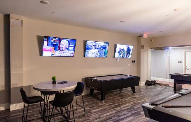 a game room with a pool table and televisions on the wall