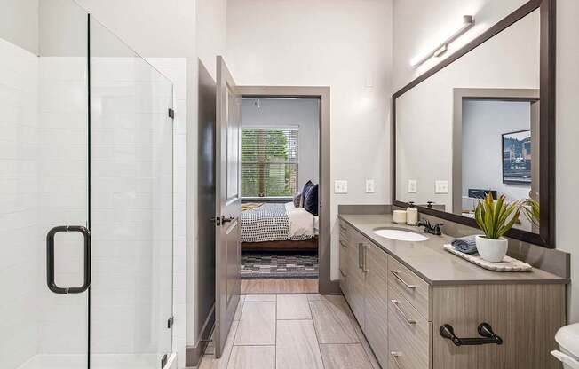 A bathroom with a glass shower door and a wooden vanity.