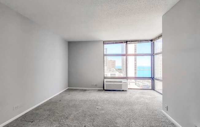 an empty room with a large window and an air conditioner