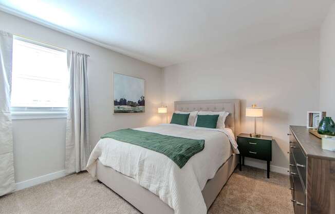 A bedroom with a large bed and a painting on the wall.