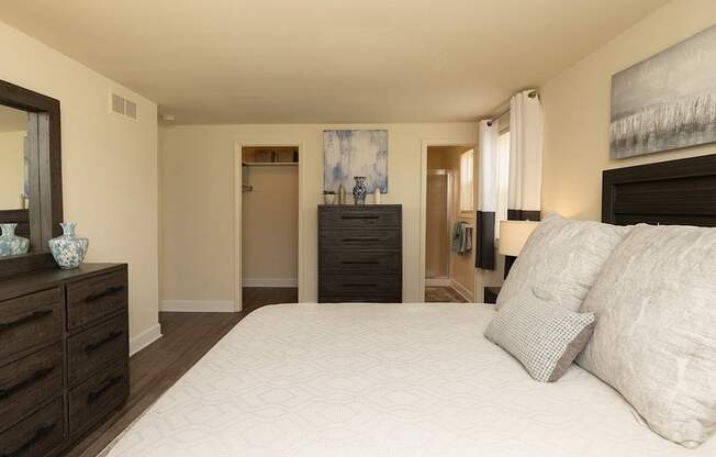 A bedroom with a large bed, a dresser, and a mirror.