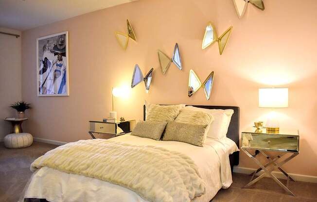 A bedroom with a large bed, a nightstand, and a table with a lamp on it.